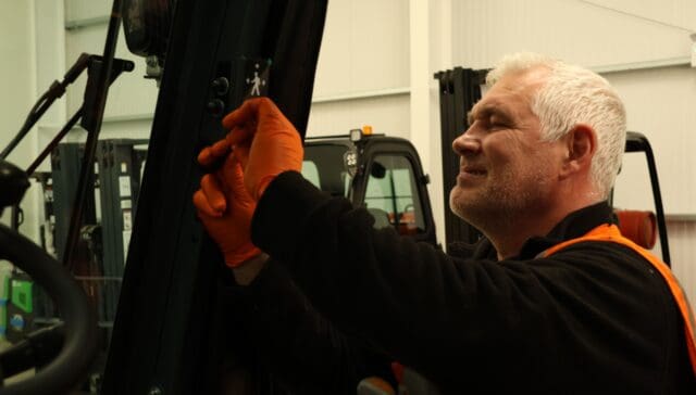 Gary Kelly installs a Safety Shield indicator onto a black forklift truck